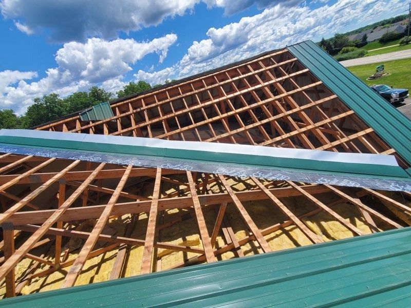 A roof is being built with a green roof and a blue sky in the background.