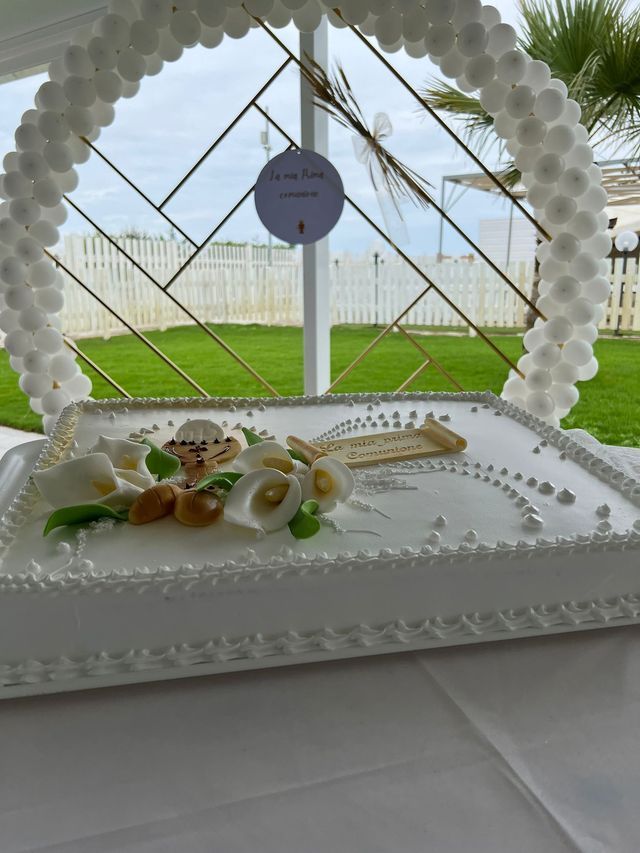 Una torta bianca con fiori e una croce sopra