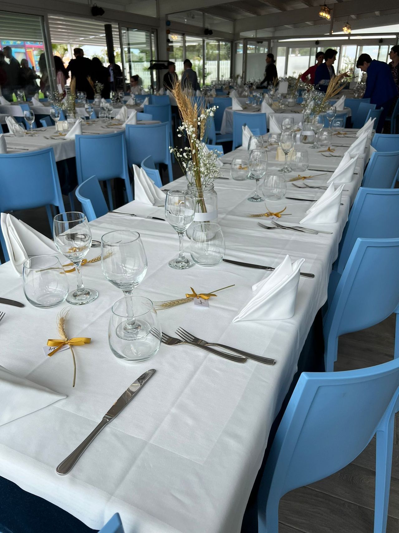 Un lungo tavolo con una tovaglia bianca e sedie blu in un ristorante.