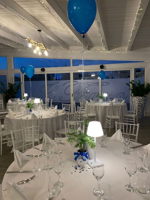 Una stanza con tavoli bianchi e palloncini blu sul soffitto