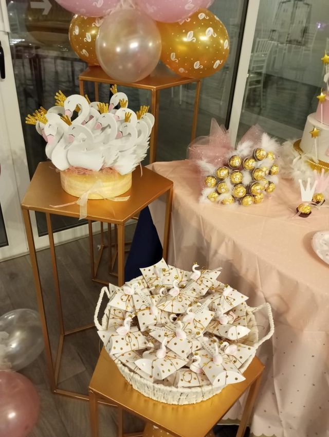 Un tavolo con sopra una torta, dei palloncini e un cesto di dolcetti.