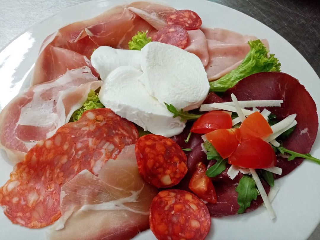 Un piatto bianco condito con una varietà di carni e verdure