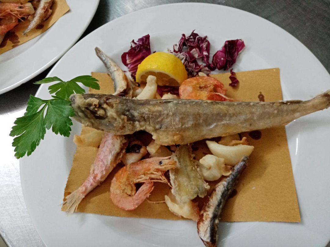 Un piatto bianco condito con pesce fritto e gamberetti