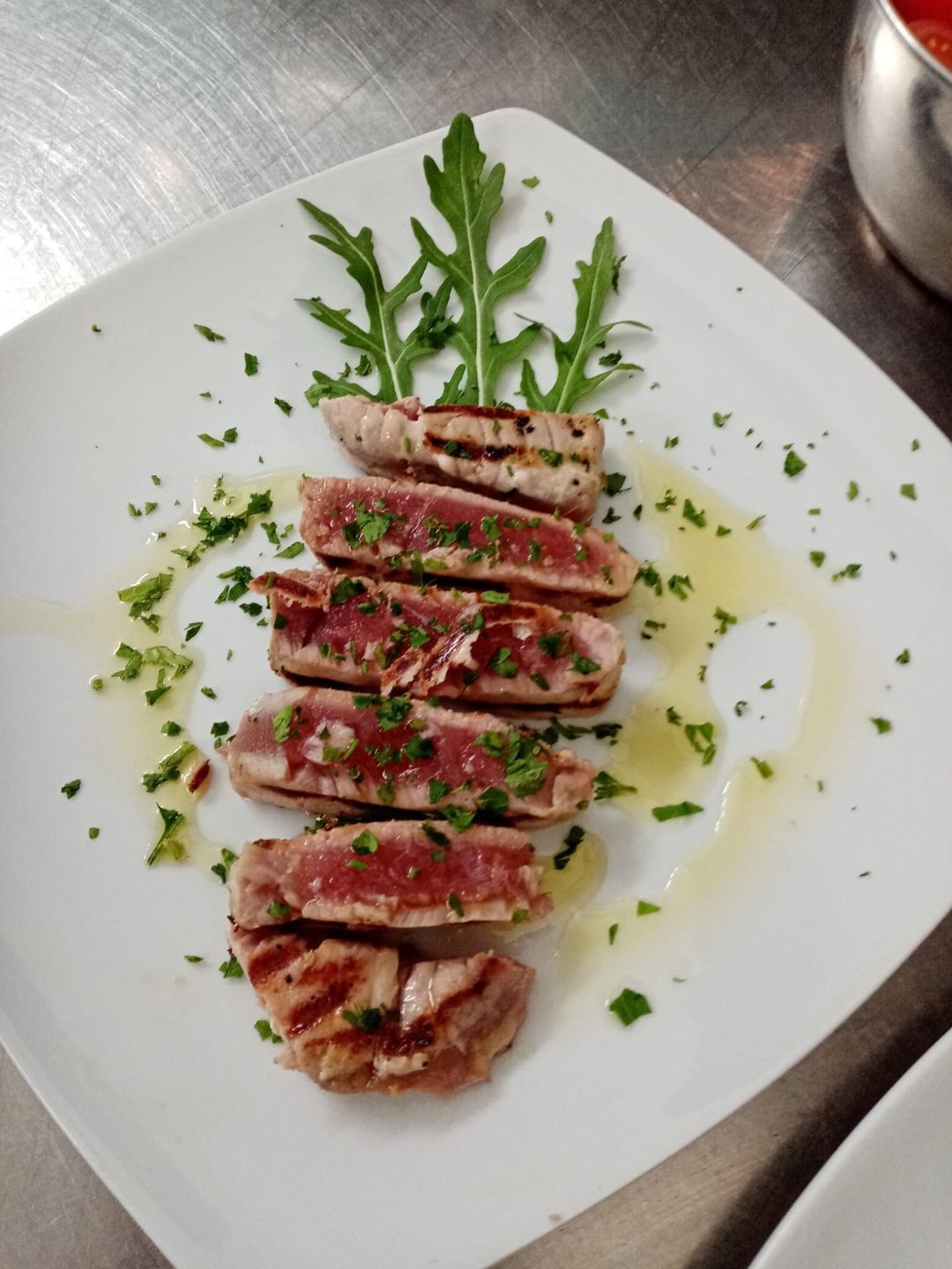 Un piatto bianco condito con carne affettata e verdure