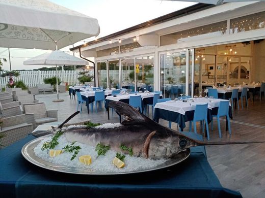 Un grosso pesce è seduto sul ghiaccio davanti a un ristorante.