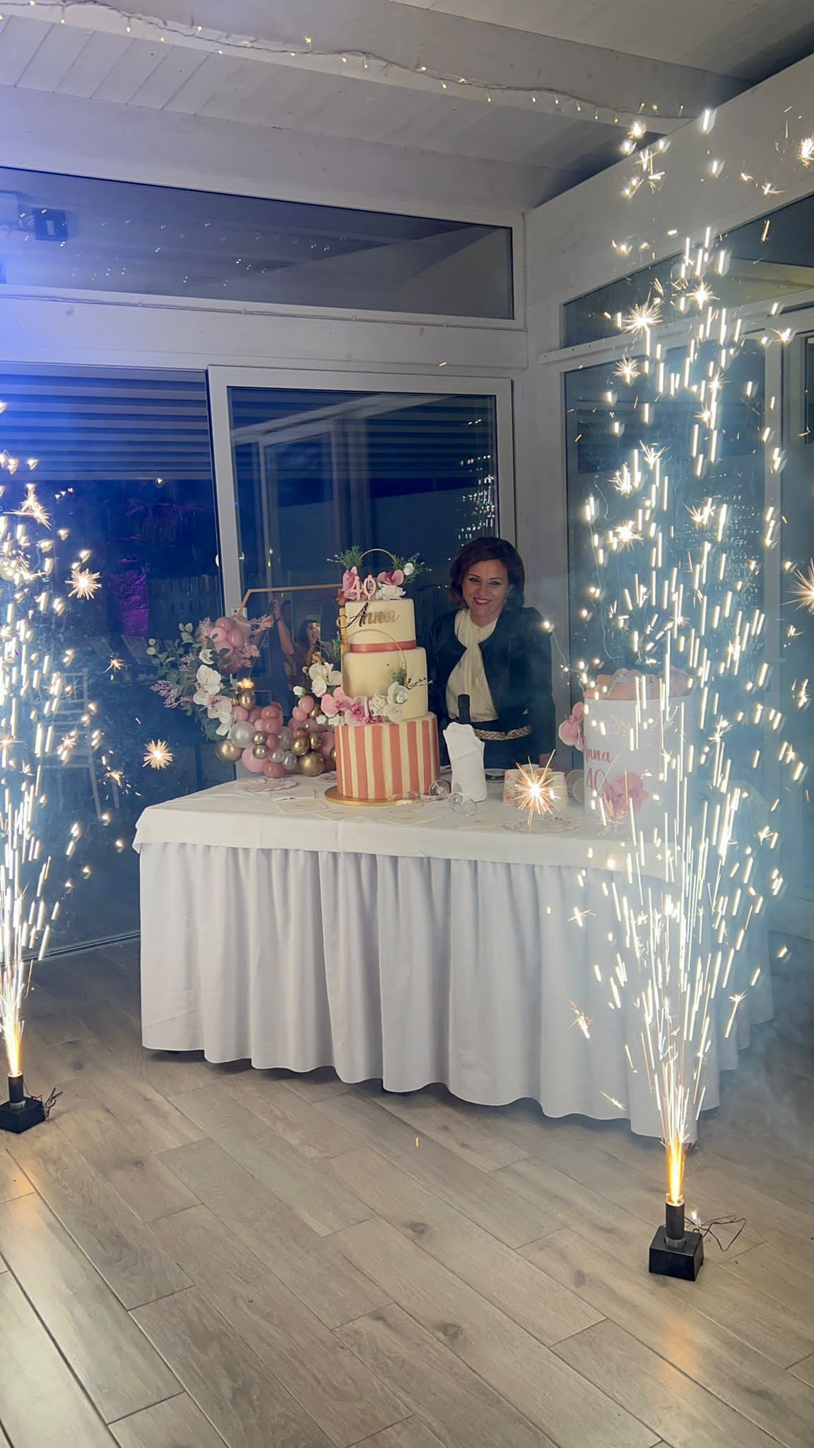 Una donna sta tagliando una torta su un tavolo con le stelle filanti sullo sfondo.