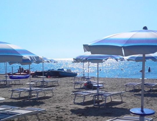 Una spiaggia con molti ombrelloni e sedie