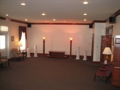 Empty room with brown carpet, white walls, and pillars. Lamps and seating are present.