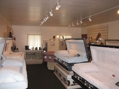 Inside a funeral home: coffins on display, lit by track lighting.