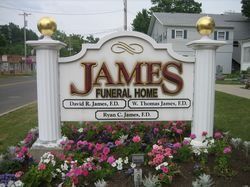 Sign for James Funeral Home; white with gold accents, floral border.