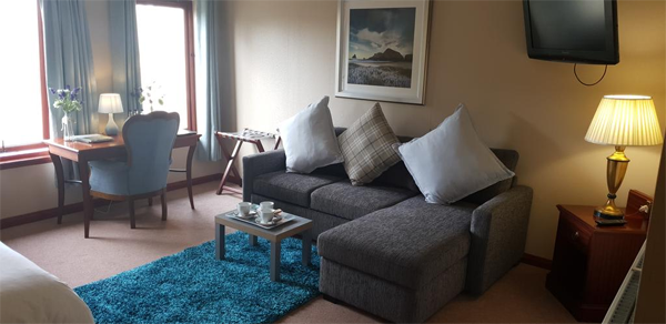 Comfortable seating area in hotel with corner couch and blue rug