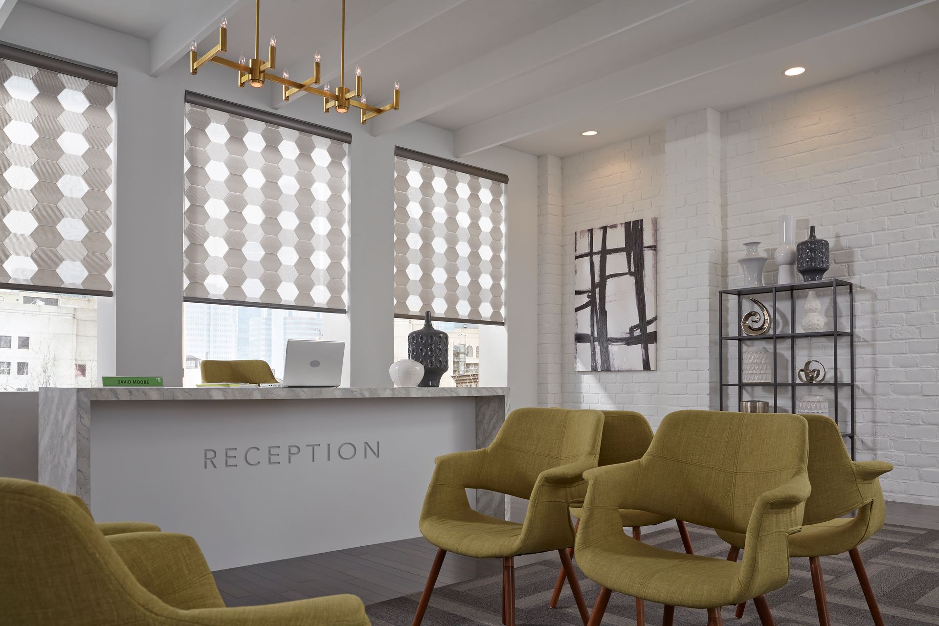 Reception area with a marble counter, gold chairs, and geometric window blinds.