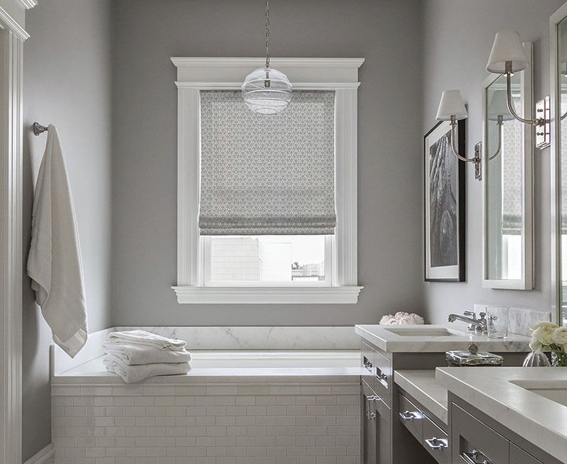 Gray bathroom with bathtub, window, and vanity. White towels, neutral walls, and globe light fixture.