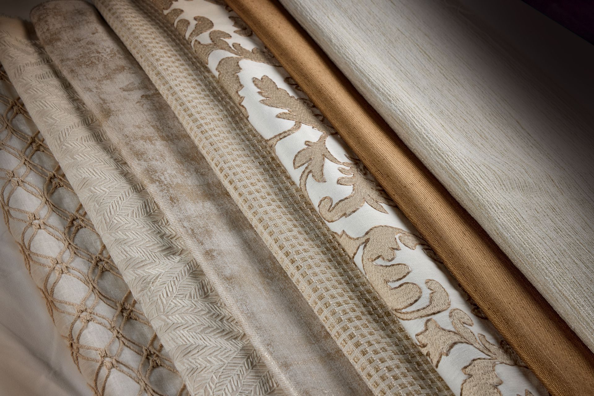 Assortment of fabric swatches in neutral tones, including patterned and textured designs.