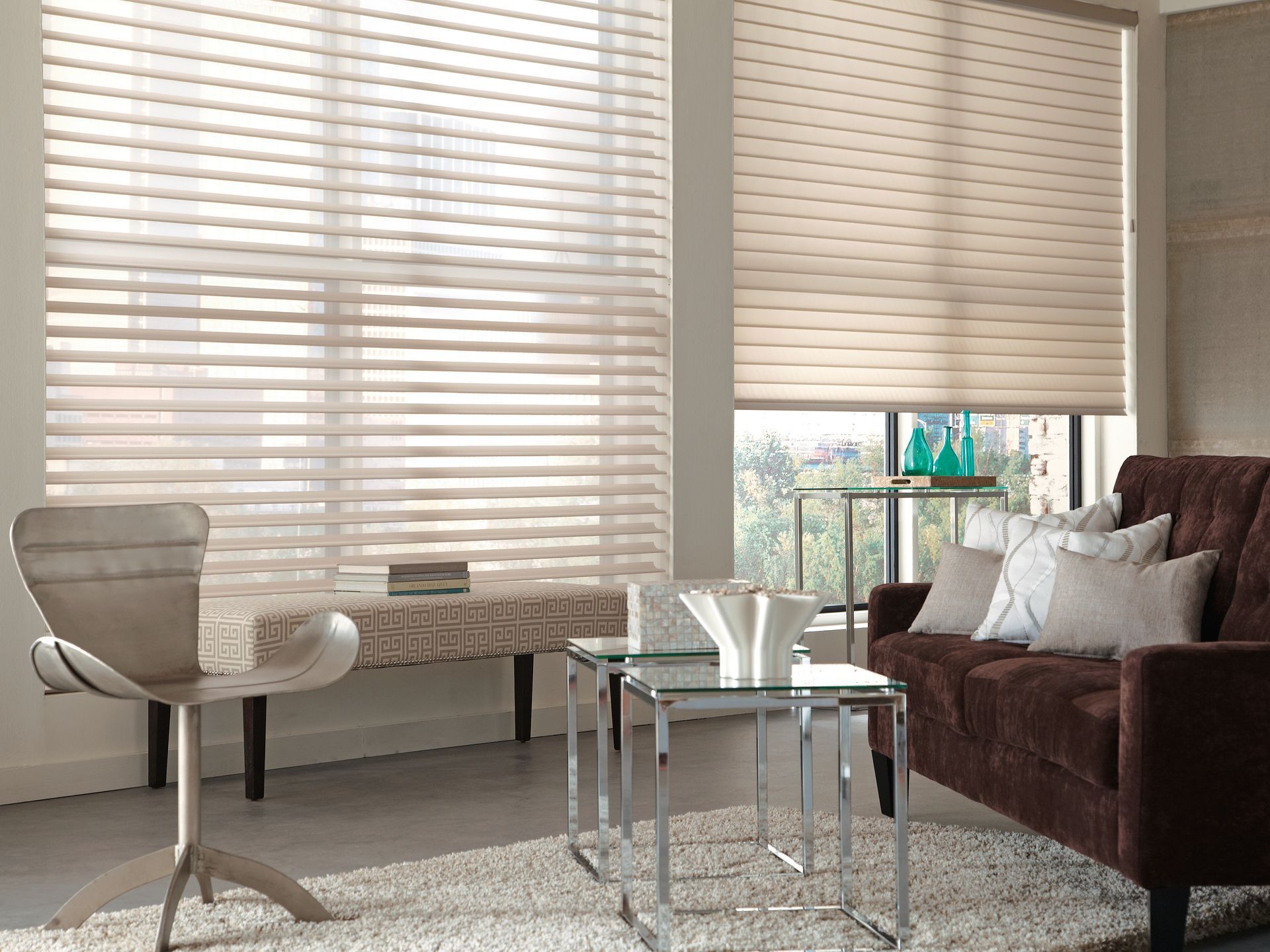 Living room with blinds, a brown sofa, glass tables, a rug, and a modern chair.