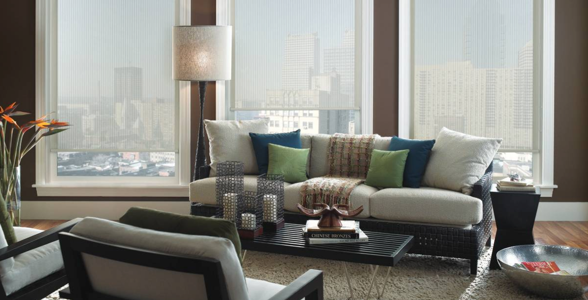 Living room with a white couch, sheer shades, and city view.