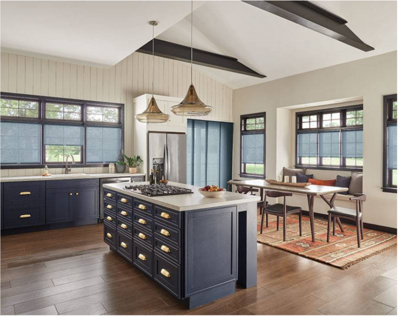 A spacious kitchen with a navy blue island, cabinets, and dark window frames. Includes a dining area and wood flooring.
