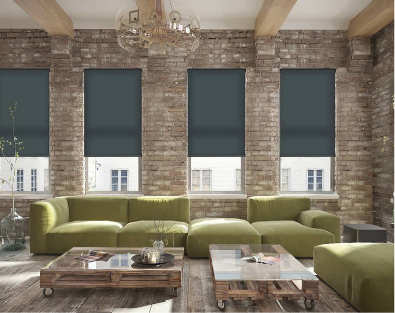 Living room with green sofa, brick wall, four windows with dark shades, wooden coffee table.