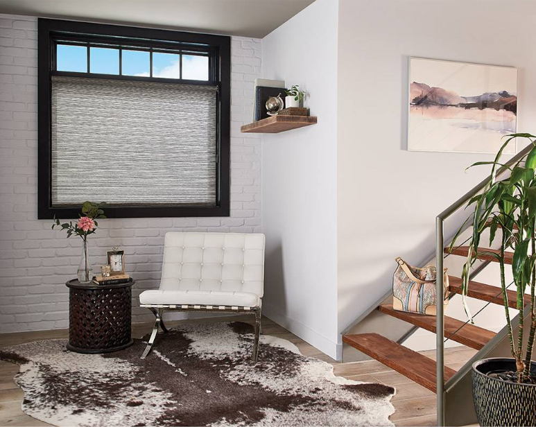 A bright, modern room with a window, white chair, and wooden staircase.