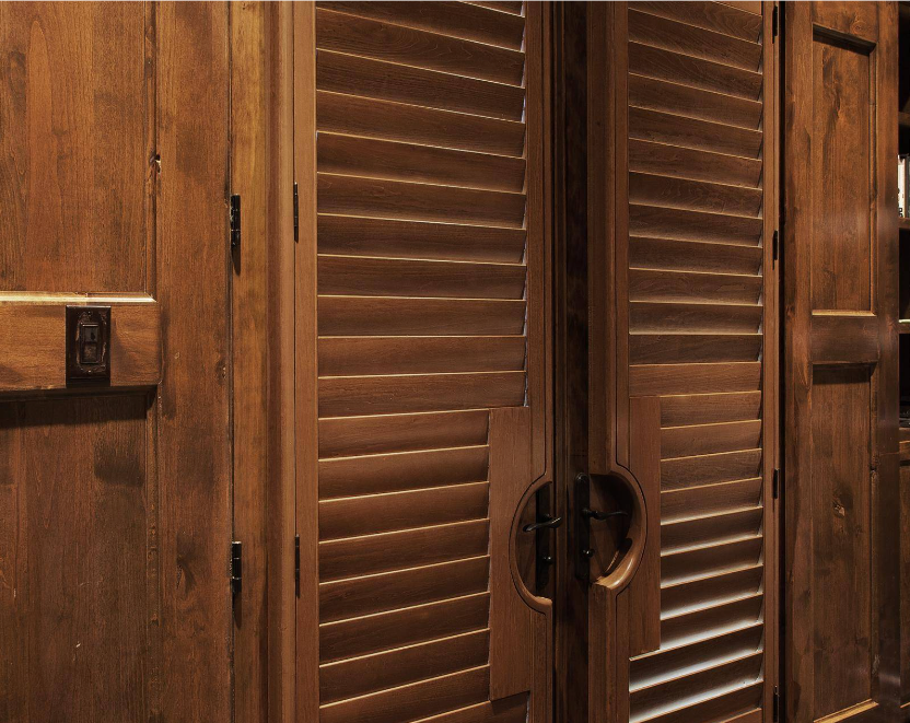 Wooden closet doors with shuttered and solid panels in a warm brown tone.