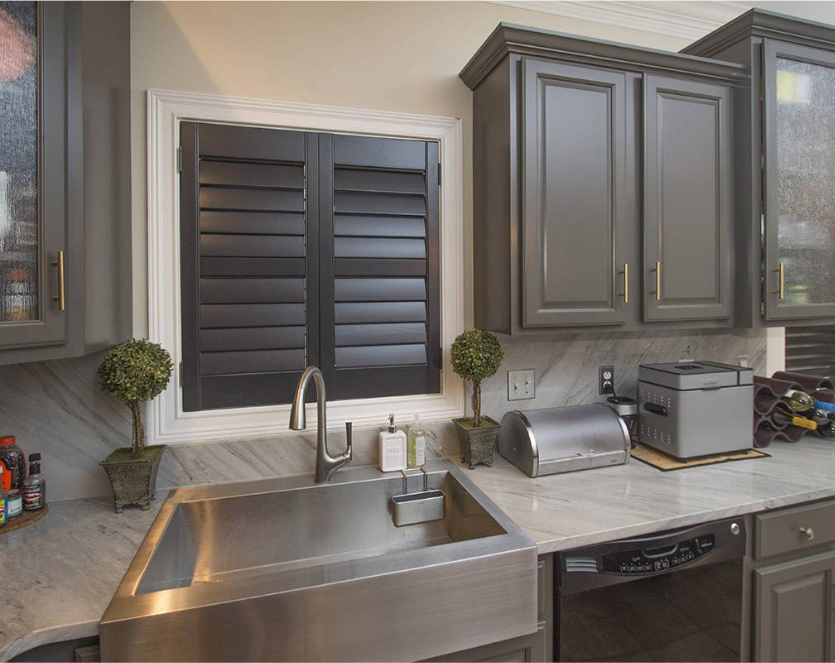 Kitchen with a stainless steel sink, dark gray cabinets, and black window shutters.