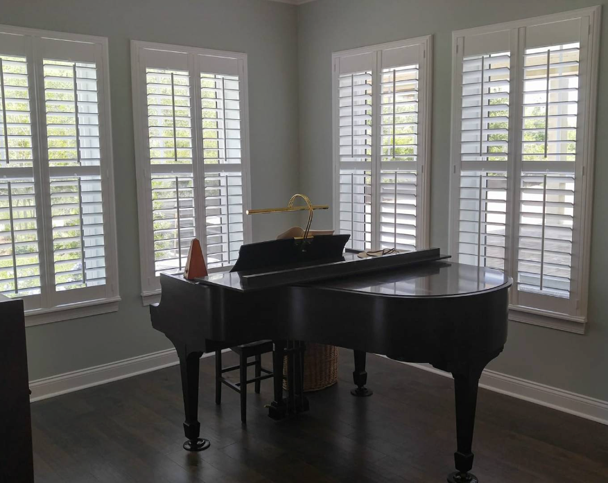 A grand piano in a room with white shutters. The walls are light blue.