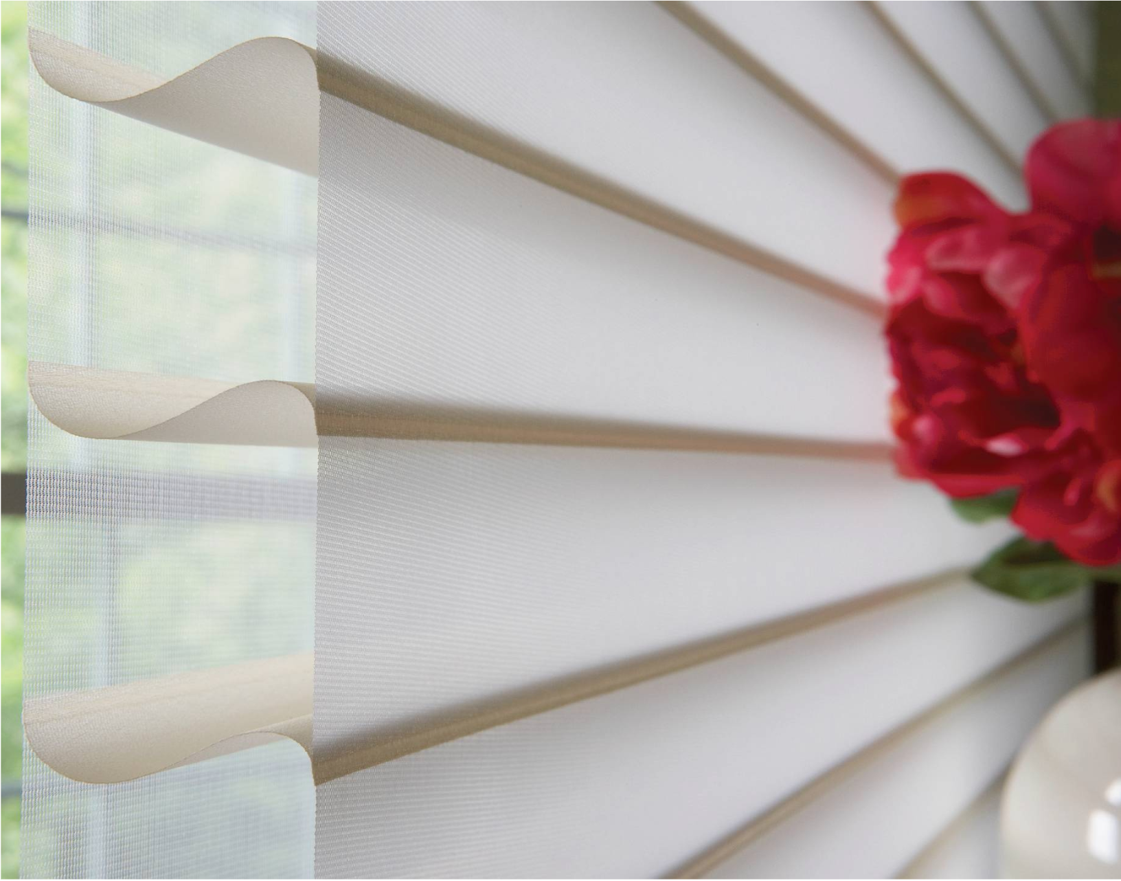 Close-up of cream-colored window blinds, with a red flower bouquet on the right.
