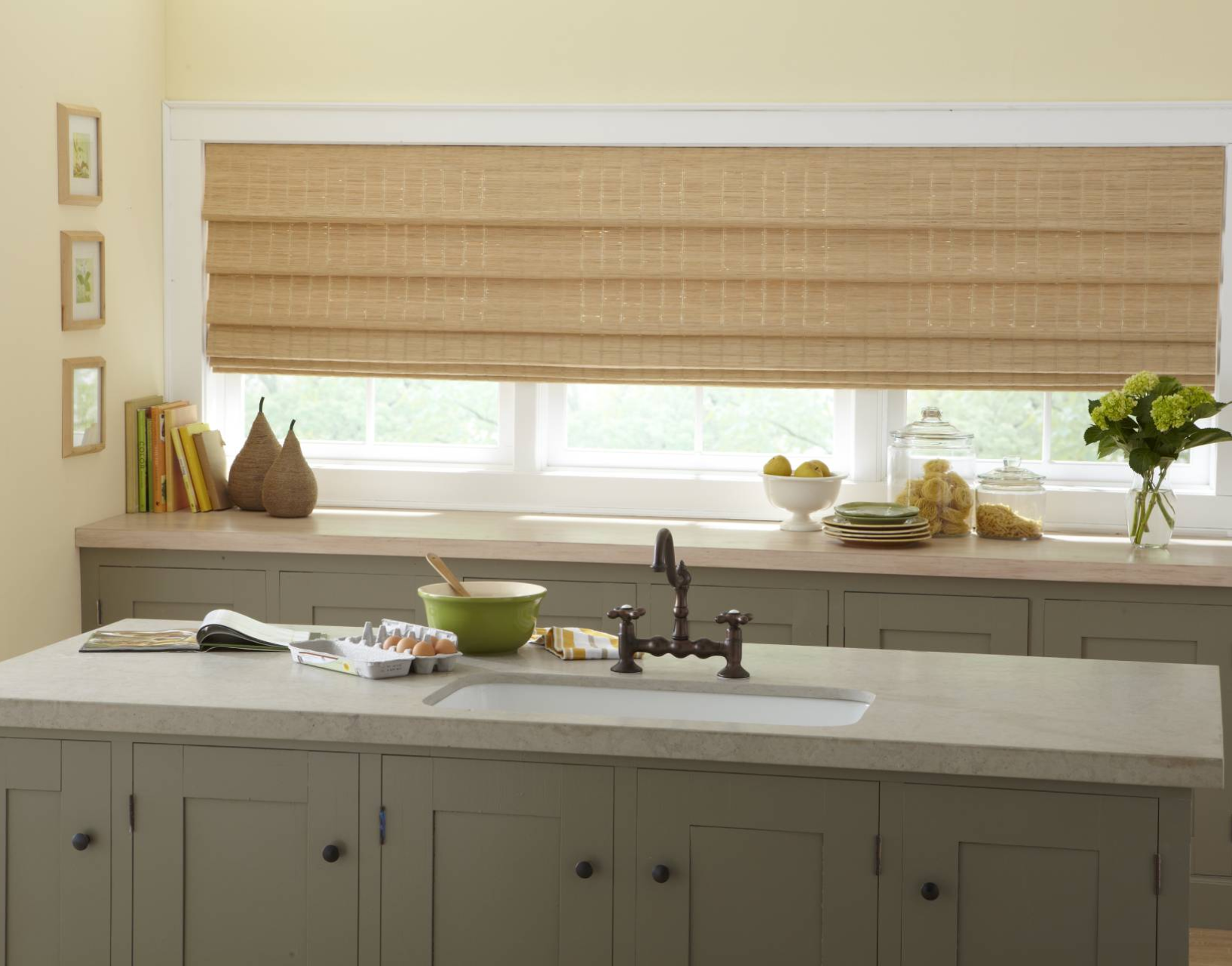 Kitchen with tan woven Roman shade, gray cabinetry, countertop, and sink.