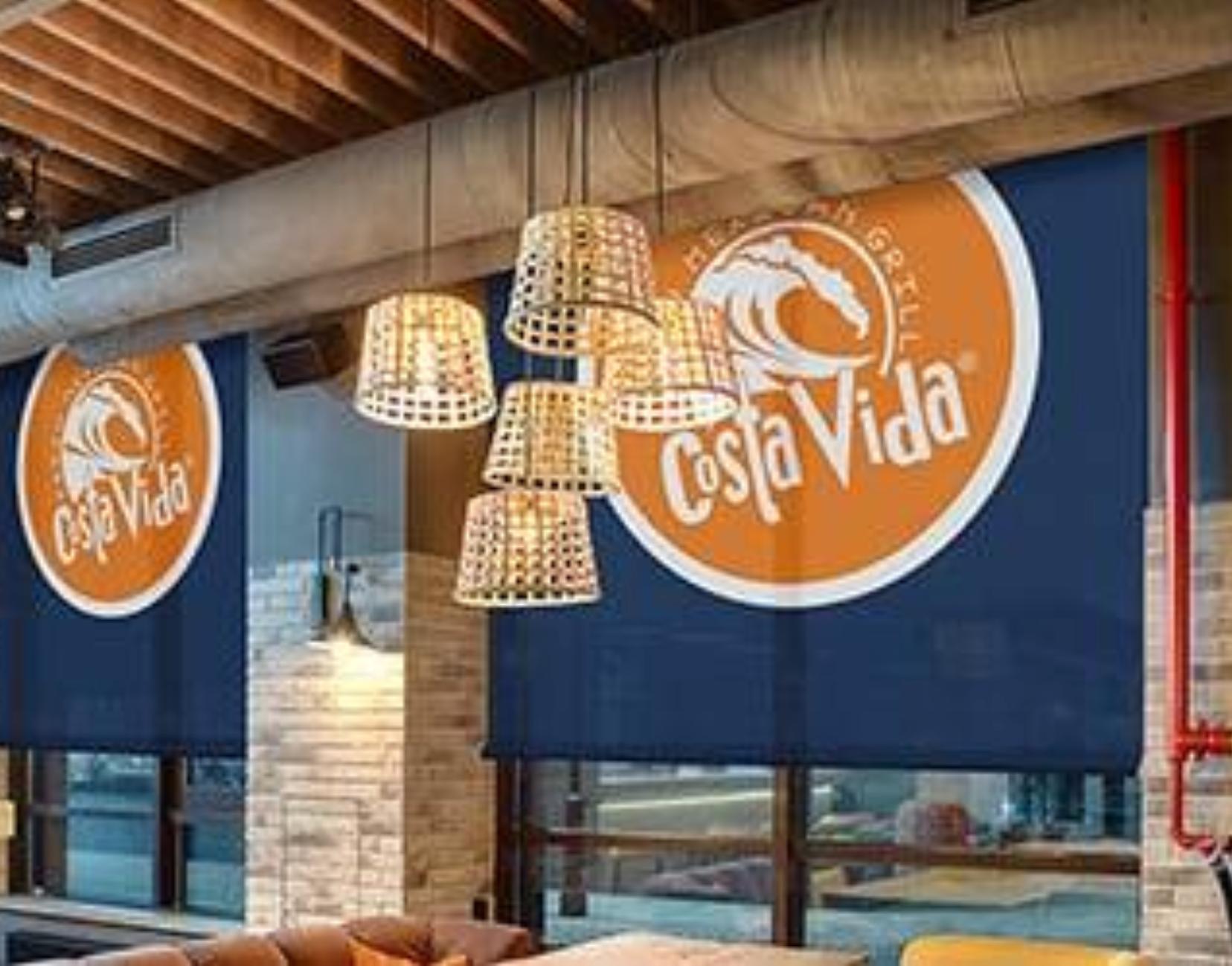 Costa Vida restaurant interior with hanging lights and brand logo on blue banners.