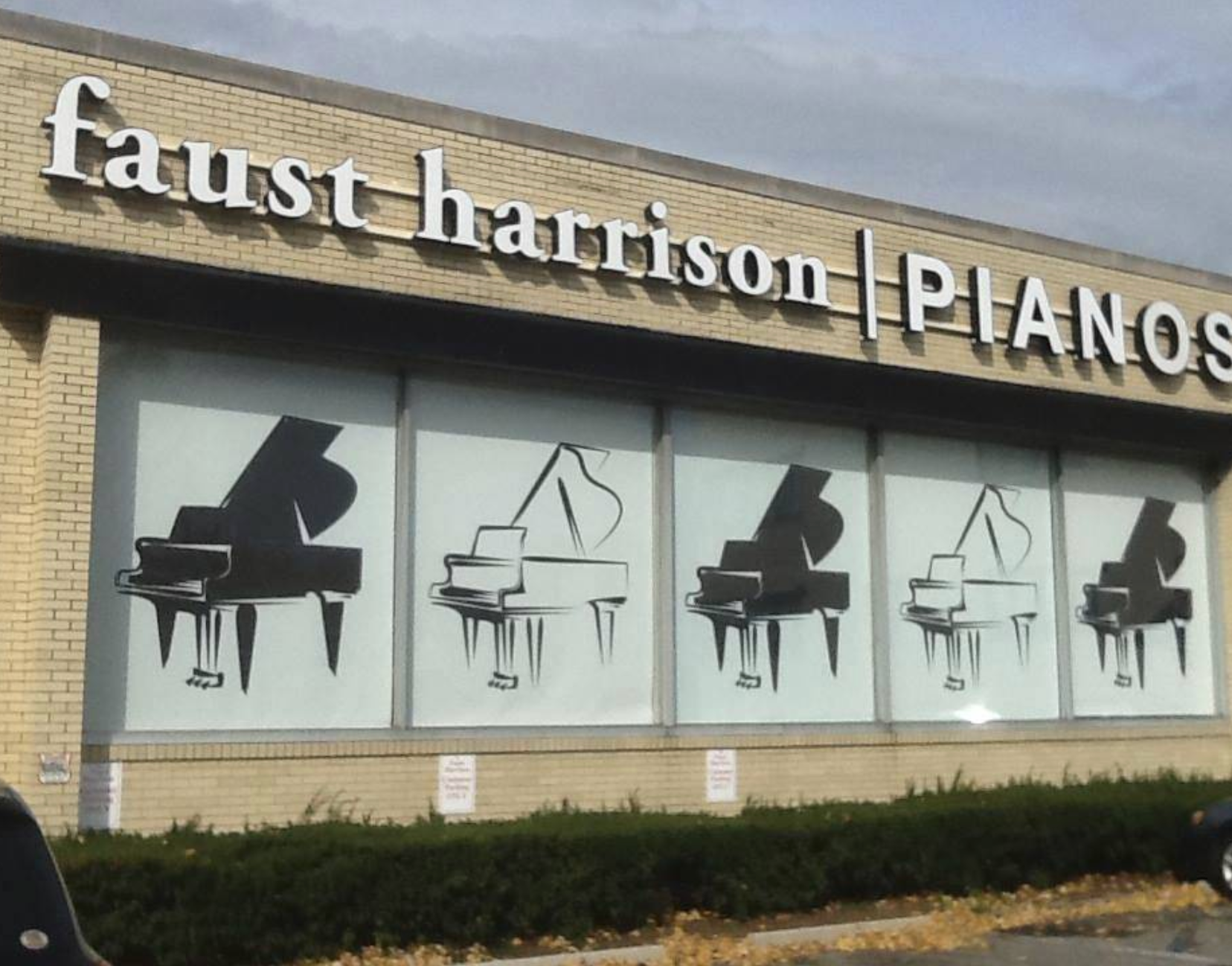 Faust Harrison Pianos storefront with four piano illustrations in the window; white sign letters.