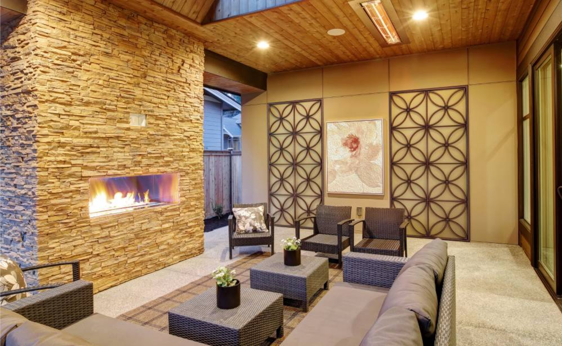 Outdoor patio with fireplace, seating area, stone wall, and decorative metal screens.