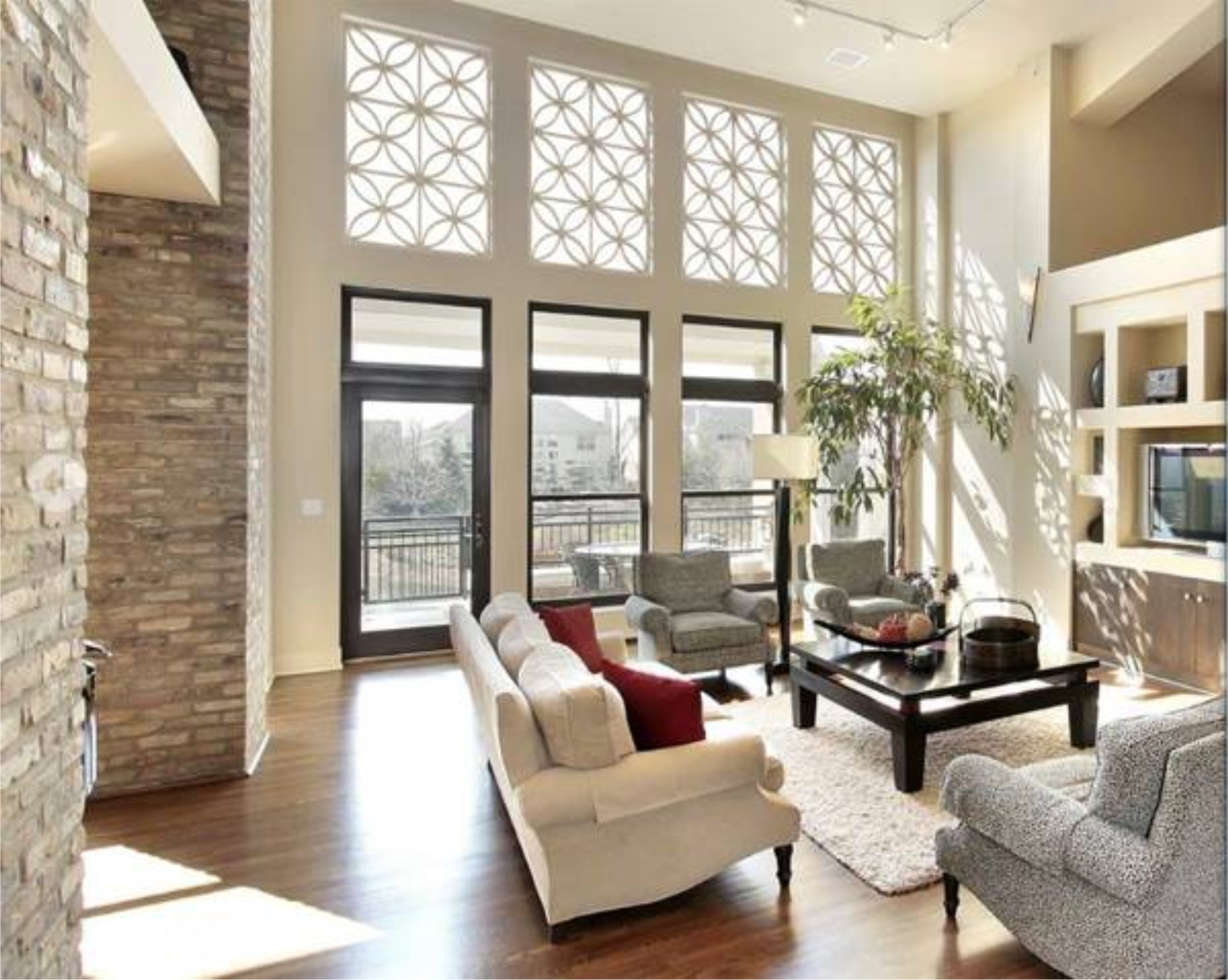 Bright living room with tall windows, brick wall, and modern furniture.