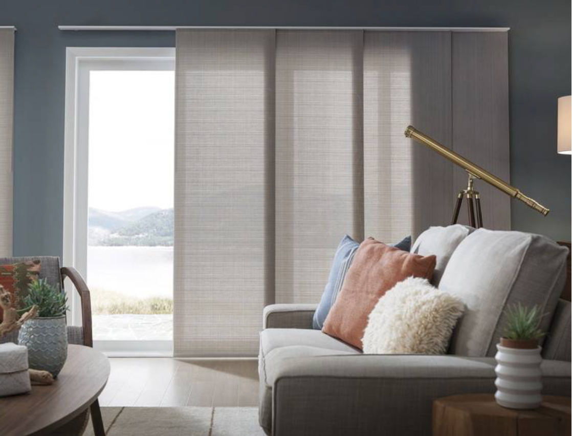 Living room with sliding door and panel blinds; gray couch, telescope, lake view.