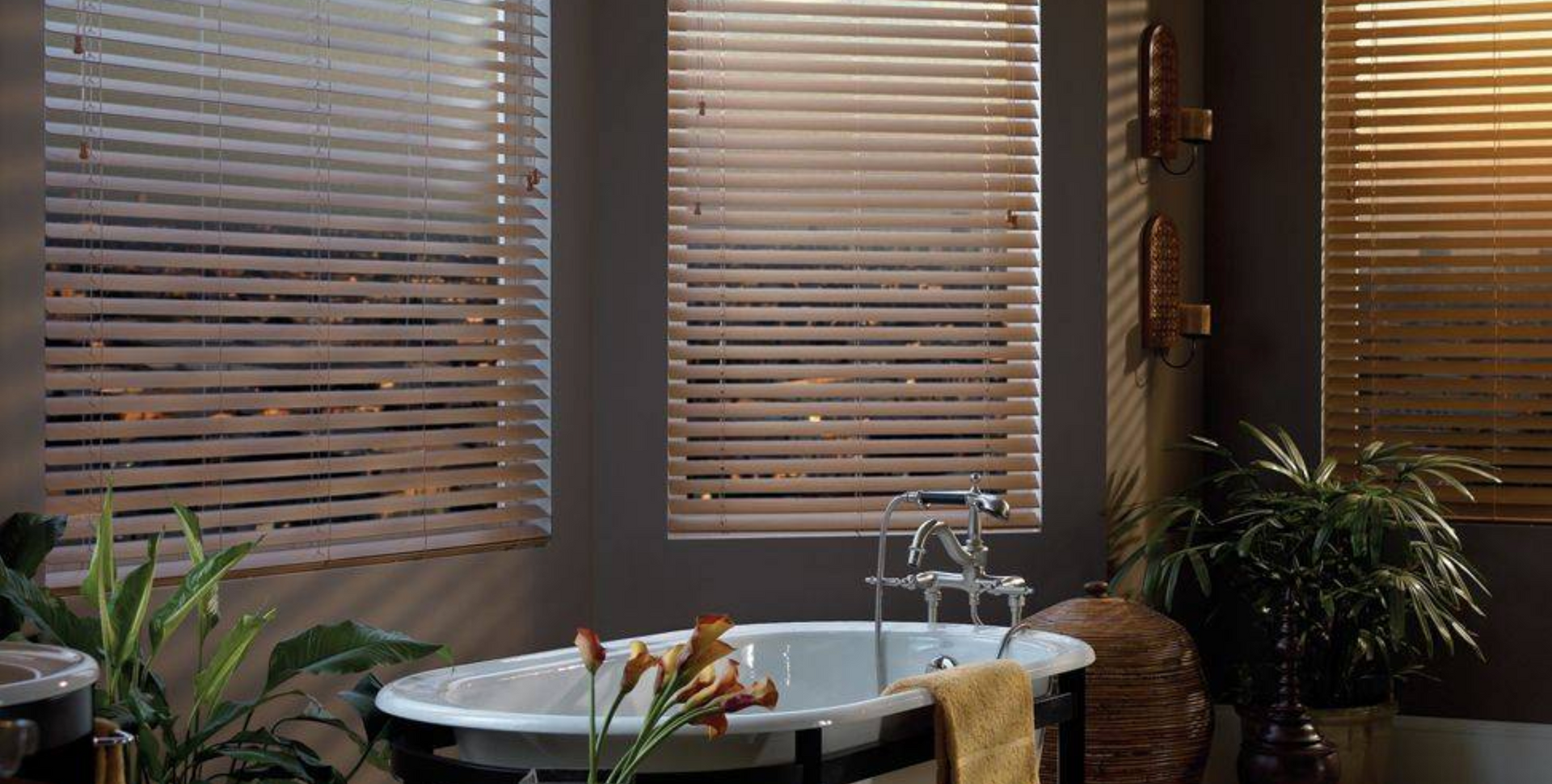 Bathroom with wooden blinds, a white tub, and plants.