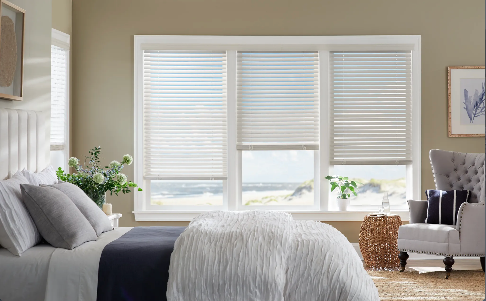 Bedroom with bed, three windows with blinds, armchair, and coastal view.