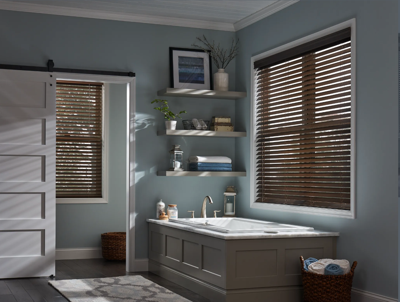 Bathroom with bathtub, wooden blinds, shelves with decor, and a sliding barn door.