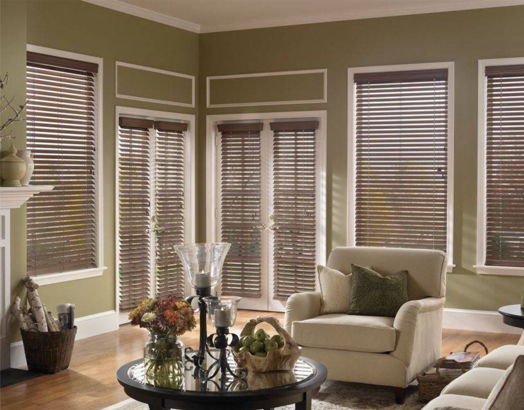 Living room with green walls, wood blinds, a fireplace, and a beige armchair.
