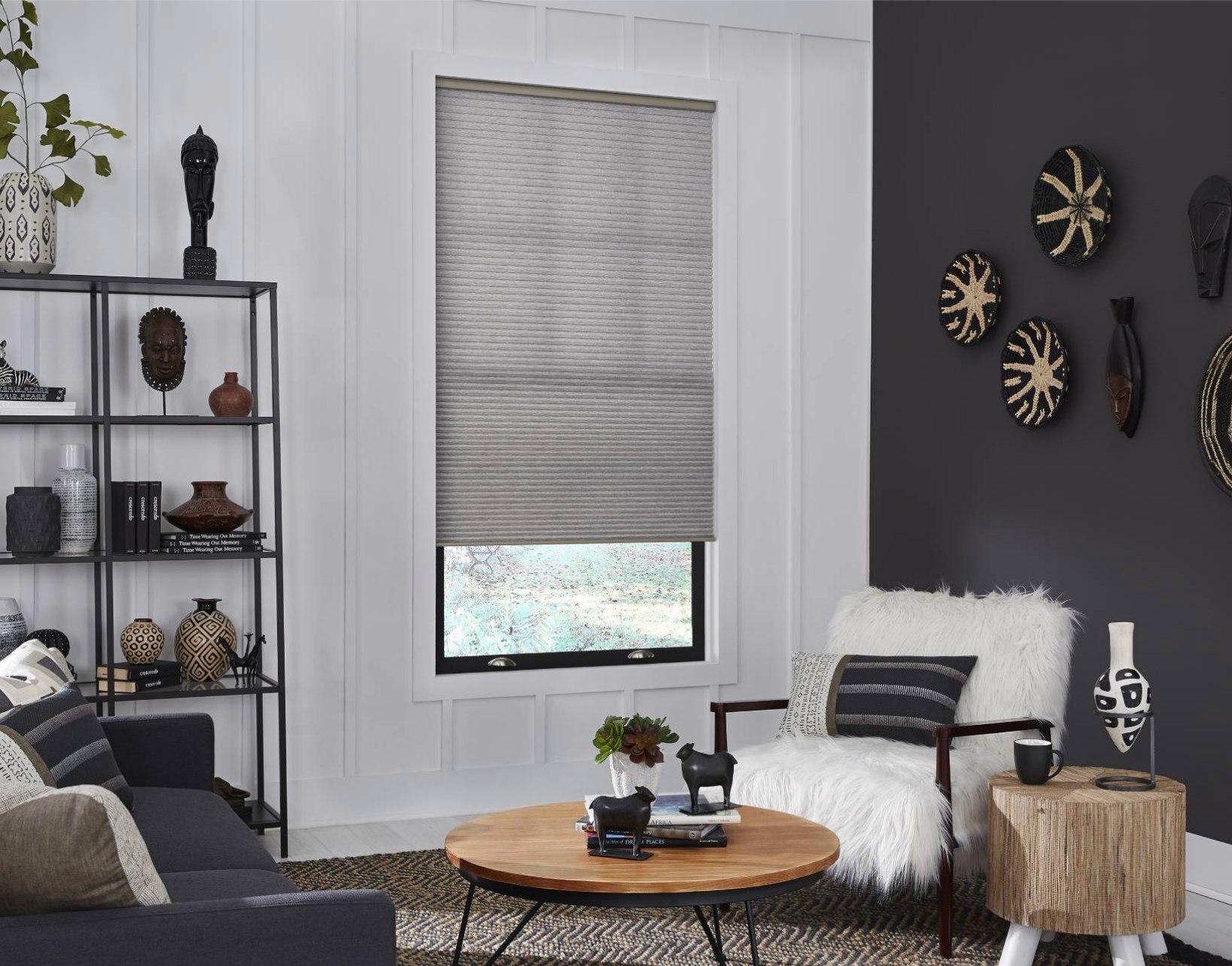 Living room with shades over window; black accent wall, shelves, and sofa; neutral decor.