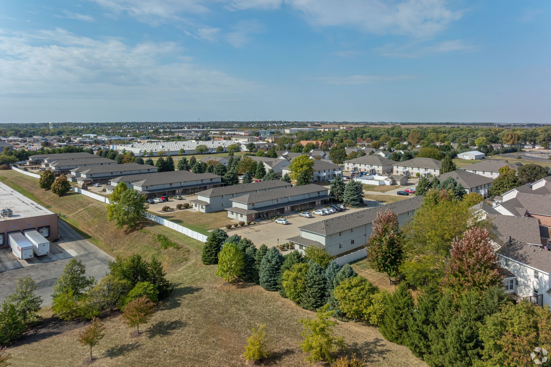 Aerial view of apartment buildings and surrounding suburban landscape under a blue sky.