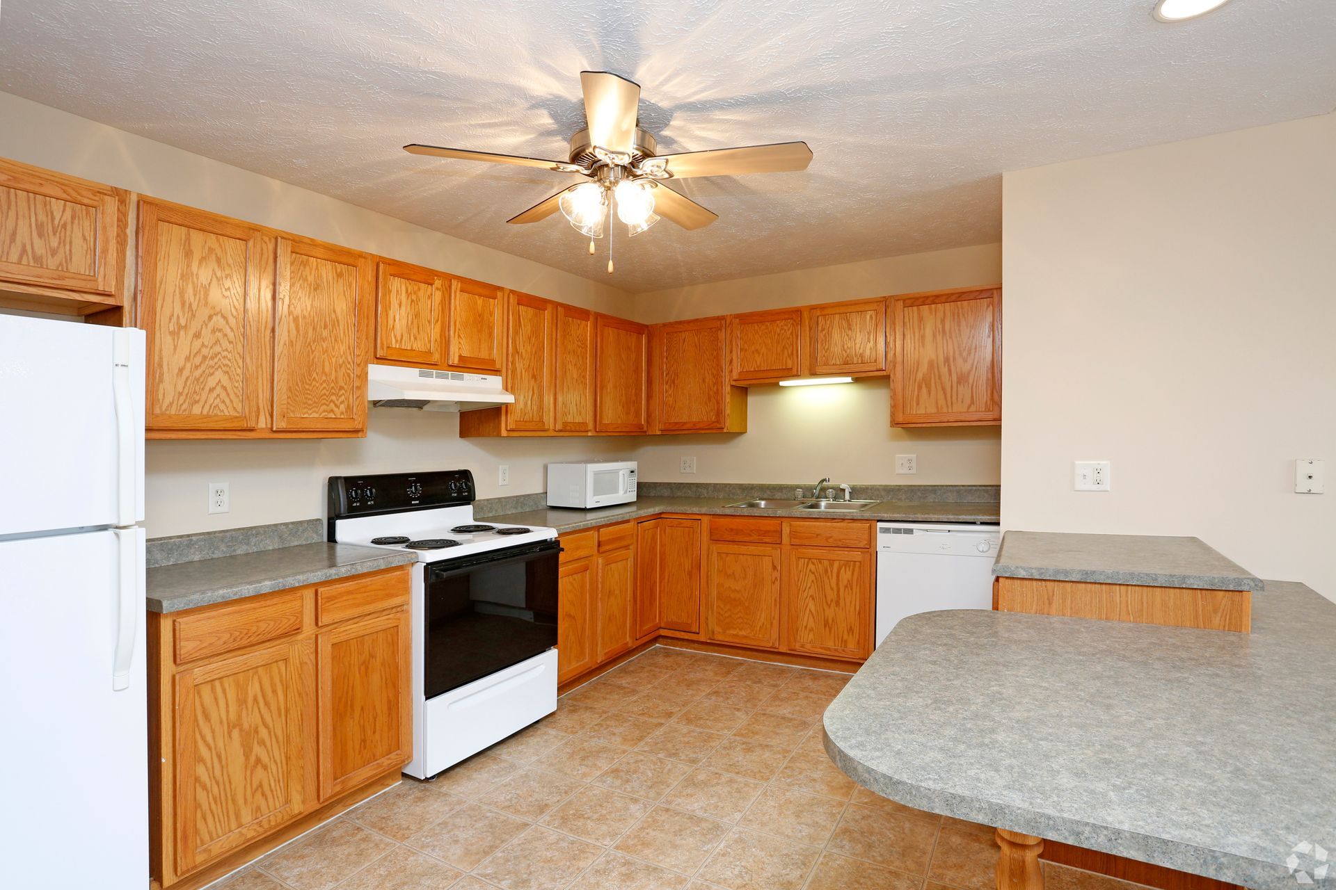Kitchen with light wood cabinets, white appliances, and a granite countertop.