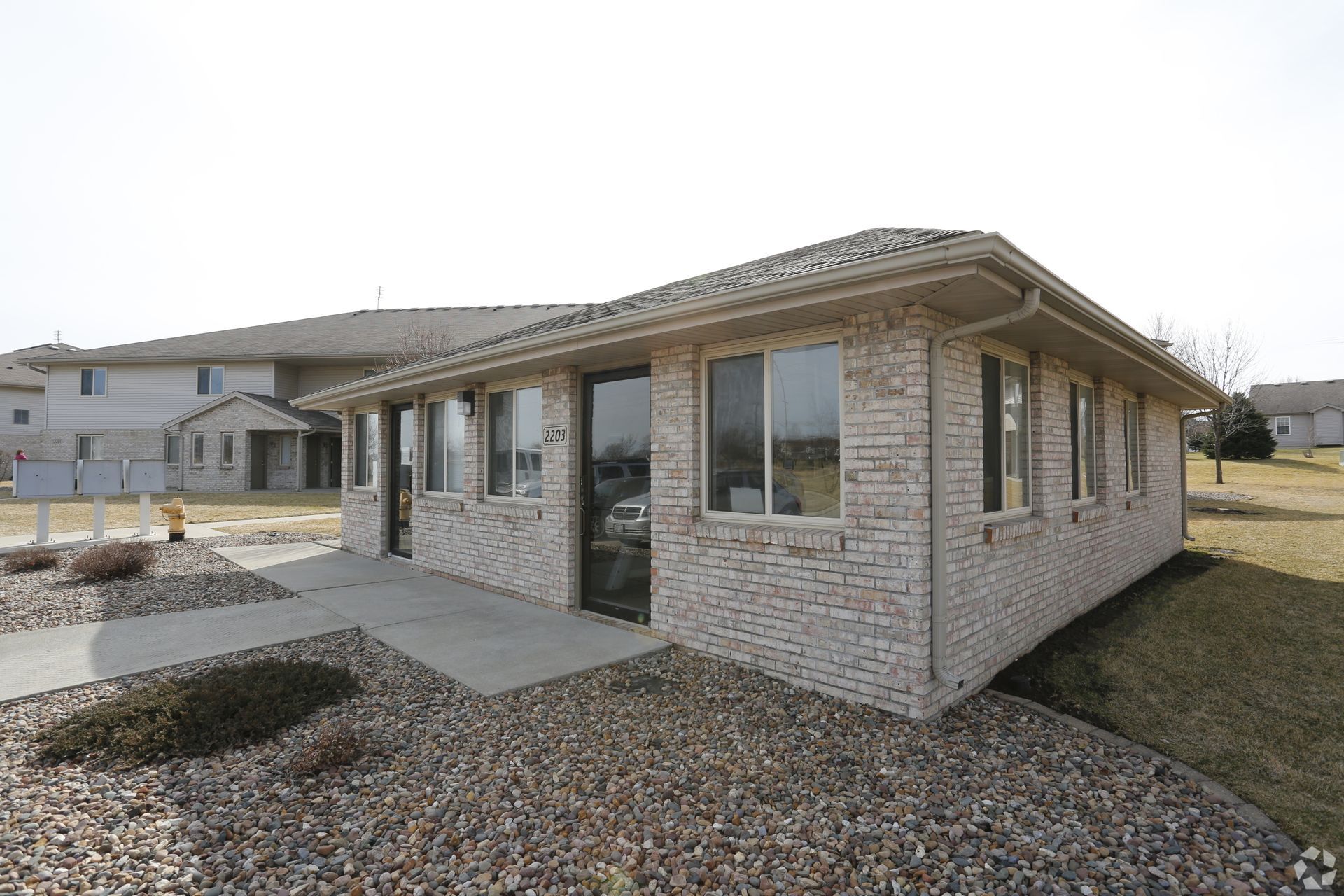 Small brick building with windows and a door, likely an office, on a grassy plot.