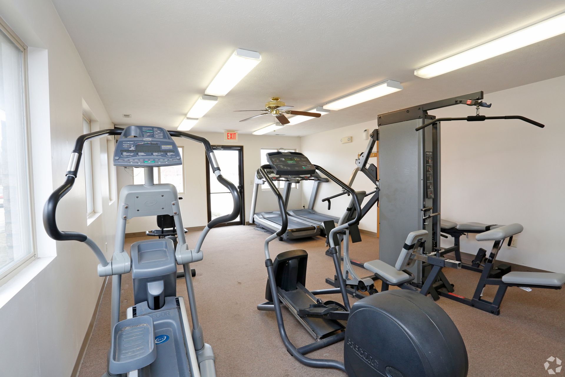 Gym with exercise equipment, including elliptical, treadmill, and weight machine.