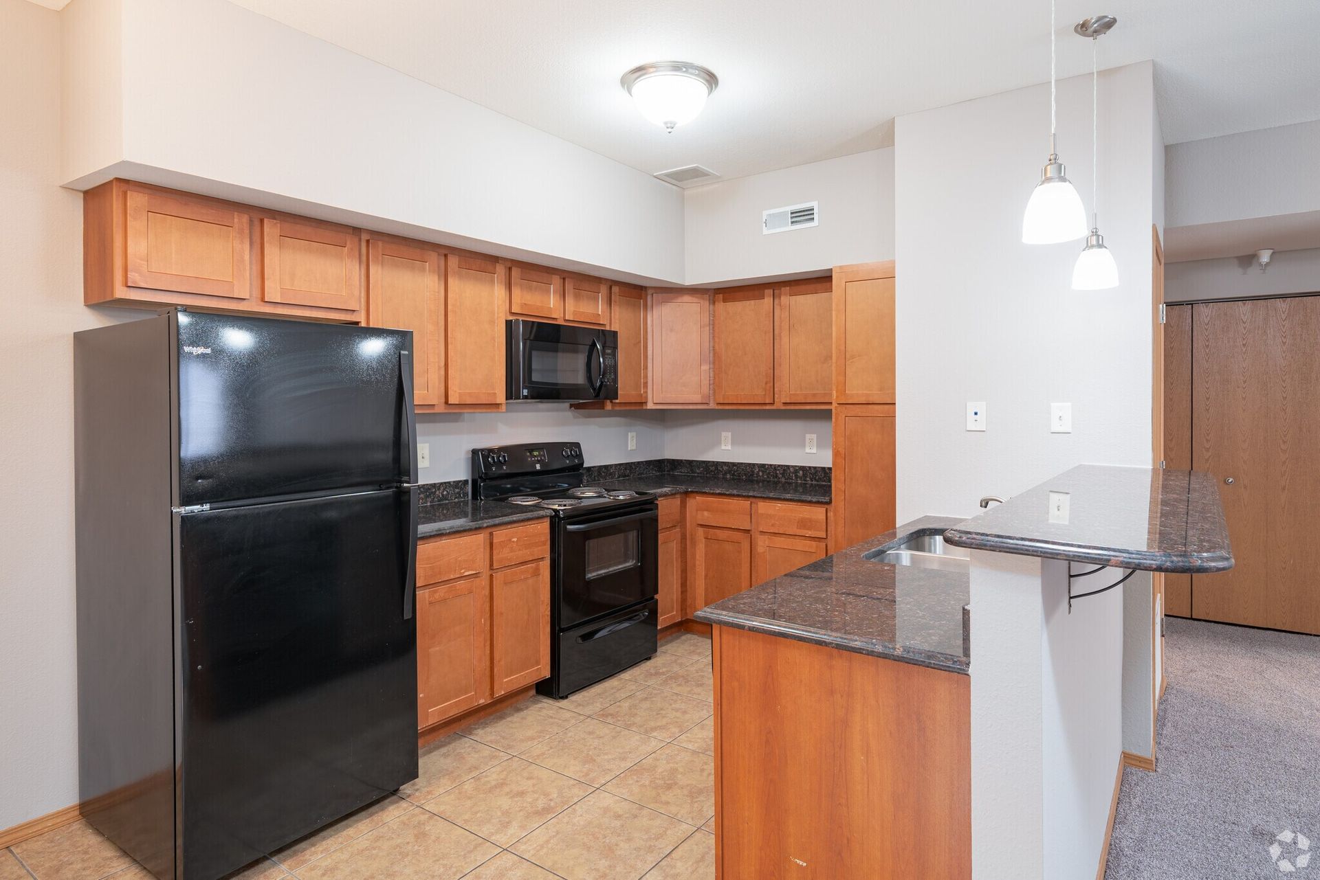 Kitchen with wooden cabinets, black appliances, and granite countertops.