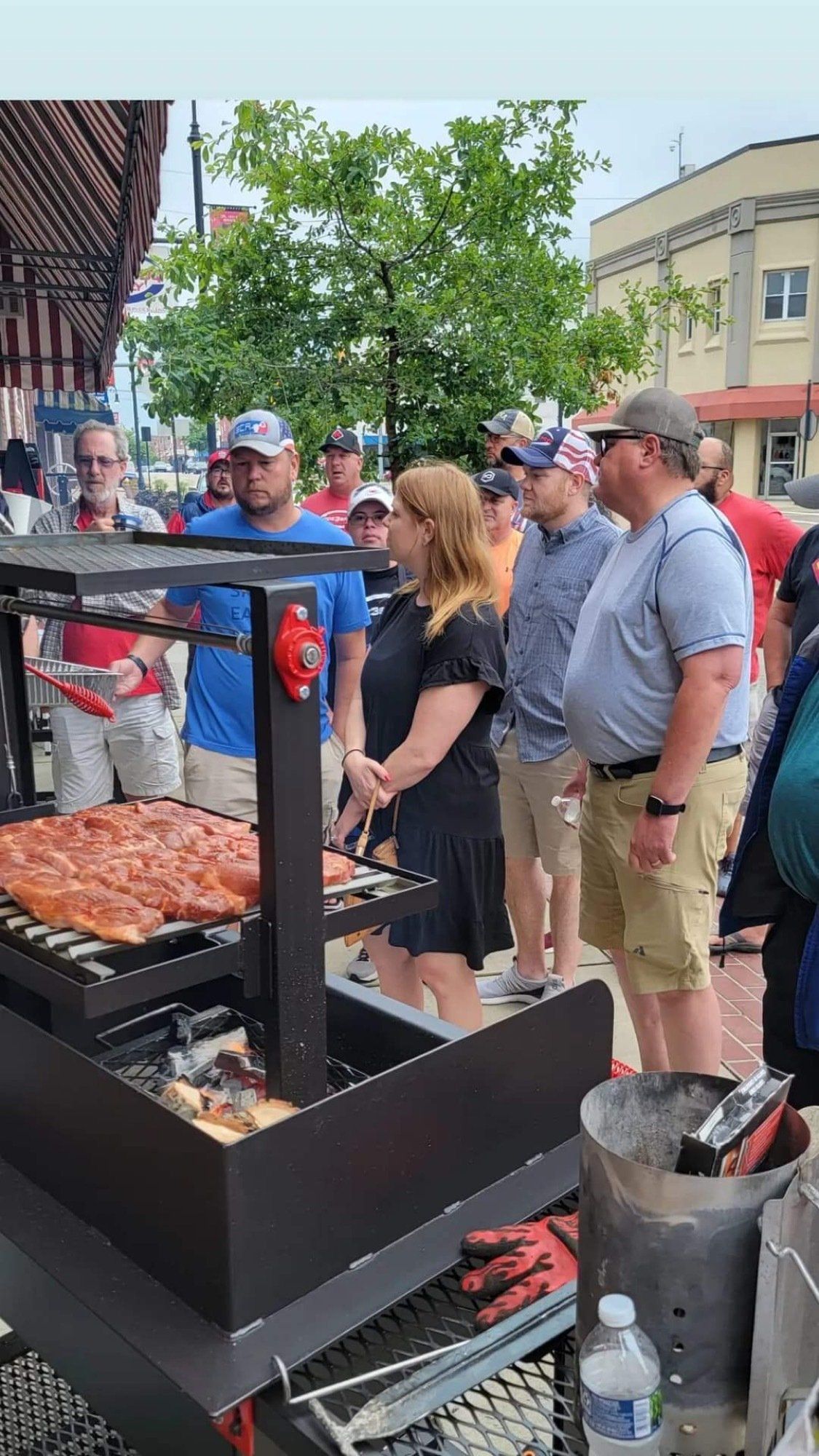 A group of people are standing around a large grill.