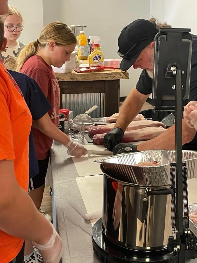 A group of people are standing around a table preparing food.