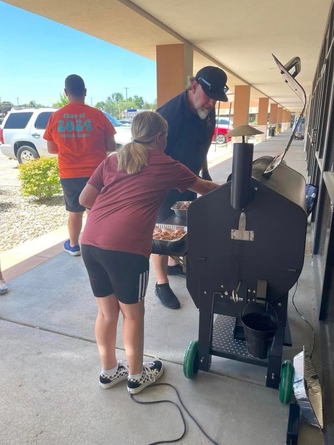 A man and a girl are standing in front of a grill.