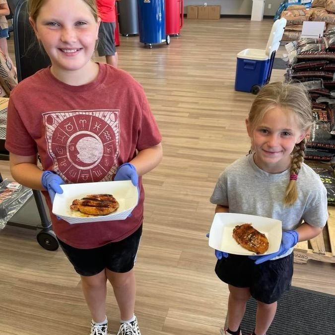 Two young girls holding plates of food in a store