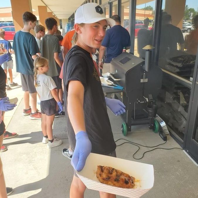 A boy is holding a tray of food in front of a group of people