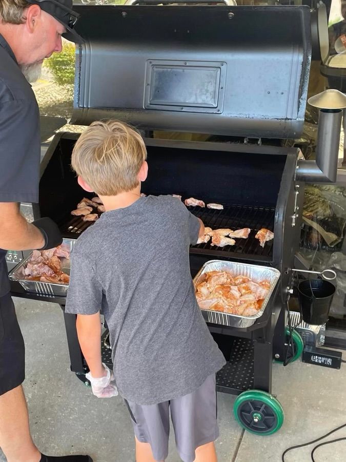 A man and a boy are cooking food on a grill.