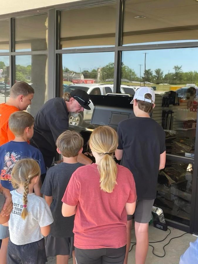A group of people are standing in front of a store looking at a grill.